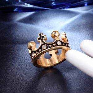 Détail d'une bague couronne dorée avec une croix et des cristaux brillants