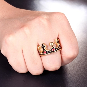 Vue détaillée bague couronne dorée avec rubis rouge et motifs de croix noires