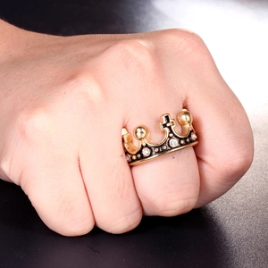 Détail d'une bague couronne dorée avec croix et zircons blancs sur un doigt d'homme