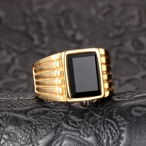 Detailed view of men's gold plated steel ring with large black rectangular gemstone