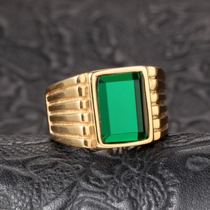 Detailed close-up of a gold-plated signet ring with emerald green stone and ribbed texture