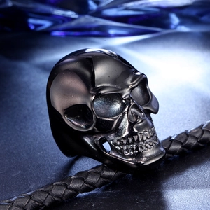 Detailed view of polished black skull ring on textured black leather cord background