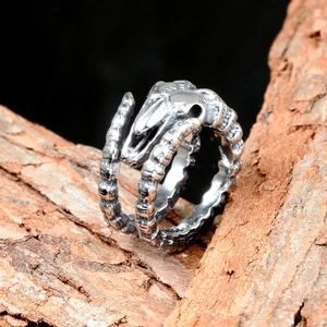 Detail view of gothic snake bone ring featuring a realistic skull on rustic wood