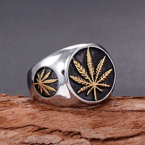 Polished stainless steel men's ring with golden hemp leaf motifs on natural wood background