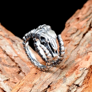 Macro shot of gothic sheep skull ring with vintage silver finish on natural tree bark