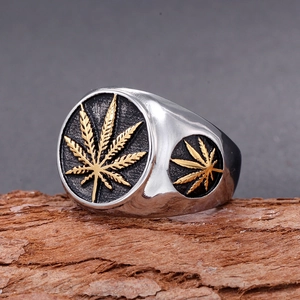 Macro detail of men's stainless steel seal ring with gold leaf relief on wood