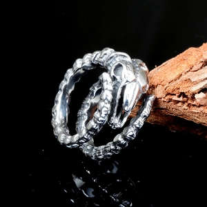 Macro detail of gothic stainless steel ring featuring a bird skull and bone texture band