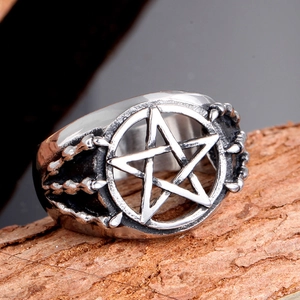 Macro detail of gothic pentagram ring featuring vintage eagle claw design in stainless steel