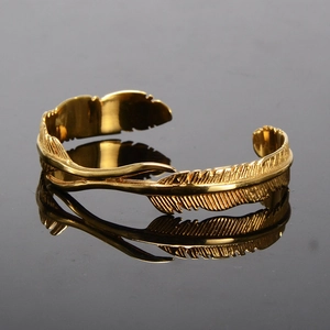 Vintage gold feather cuff bracelet in stainless steel with detailed texture on black mirror
