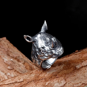Detailed close-up of a vintage silver rhino head ring on a rustic wooden branch