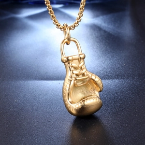 Detailopname van gouden bokshandschoen hanger met textuurstiksels en een stevige schakelketting