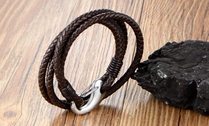 Macro view of men's multi-layer braided leather bracelet with silver metal anchor clasp