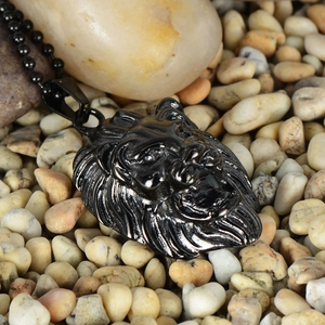 Detailed view of vintage lion head pendant in black finish on pebble background