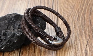 Close-up of multi-layer dark brown braided leather bracelet with silver metal clasp on rock