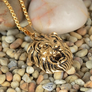 Detailed view of vintage gold lion head pendant with intricate mane texture on pebbles