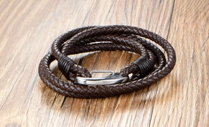 Macro view of a triple-layer braided dark brown leather bracelet with silver steel clasp