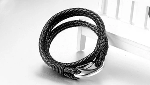 Detail of black woven leather bracelet with polished silver fish hook clasp on stand
