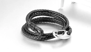 Macro detail of men's black braided leather bracelet with silver metal hook clasp