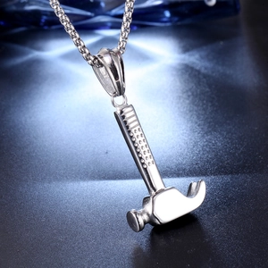 Macro shot of silver hammer pendant necklace with textured handle on dark background