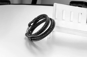 Detail of multi-layer braided black leather bracelet with silver metal magnetic clasp