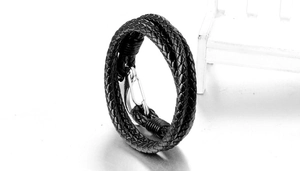 Macro view of multi-layer black braided leather bracelet with silver shackle clasp