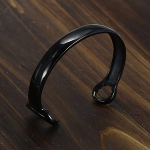 Punk style wrench cuff bracelet in black stainless steel on a dark wooden background