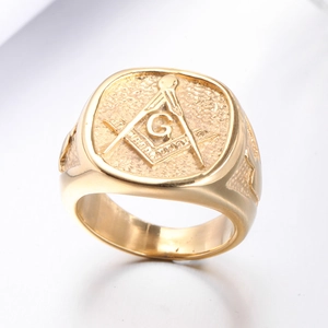 Gold Freemasonry signet ring with square and compass G symbol on brushed metal surface