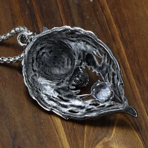 Detail of Gothic leaf pendant with diamond-cut crystal on a dark wooden background