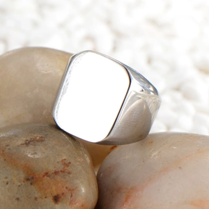 Polished silver titanium steel square signet ring for men on natural pebbles background