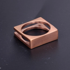 Macro view of square stainless steel ring with brushed rose gold finish texture