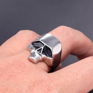Close-up of a silver-toned skull ring on hand featuring punk gothic design details