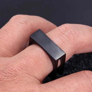 Macro shot of men's matte black stainless steel square signet ring on finger