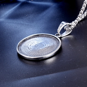 Vue macro d'un pendentif circulaire argenté à texture spirale et chaîne box