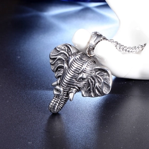 Detail of vintage silver elephant pendant with intricate carvings on a display stand
