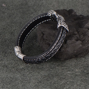 Braided black leather bracelet with silver metal carving on black volcanic stone