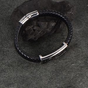 Men's braided black leather bracelet with silver stainless steel clasp on a dark stone