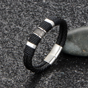 Men's multilayer black braided leather bracelet with silver metal rings on rock