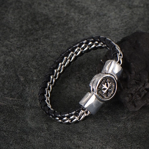 Macro detail of men's braided black leather and silver metal chain bracelet with cross motif