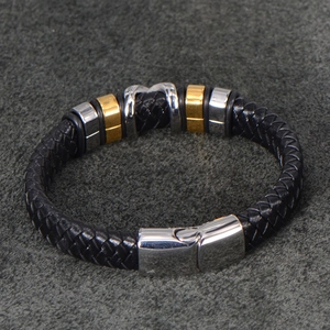Detail of black braided leather men's bracelet with silver M-shaped metal buckle
