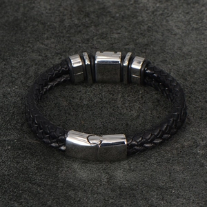 Close-up of black braided leather men's bracelet with polished stainless steel clasp