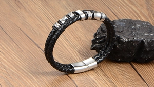 Close-up of black braided leather bracelet for men with silver steel beads on wood table