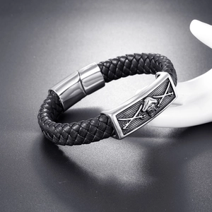 Detail of men's braided black leather bracelet featuring a silver pirate skull magnetic clasp
