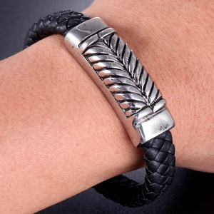 Détail macro d'un bracelet en cuir tressé pour homme avec fermoir en métal gravé plume