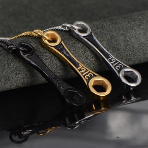 Détail macro de pendentifs clé anglaise en acier 316L en finitions noir, doré et argent