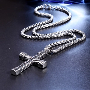 Close-up of a silver punk cross pendant with twisted metal texture and square box chain