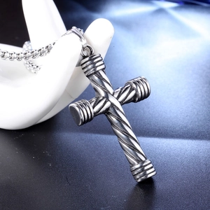 Macro detail of punk cross pendant with spiral texture and dumbbell ring accents