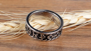 Close-up of vintage silver Buddhist ring with embossed Sanskrit symbols on textured metal