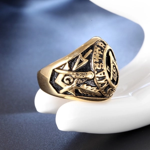Détail macro d'une bague franc-maçonne dorée avec symboles équerre et compas en émail noir