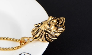 Detalle de primer plano de colgante de cabeza de león dorado con melena sobre fondo negro