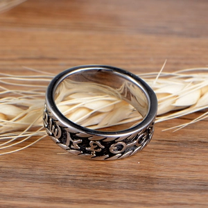 Retro stainless steel mantra ring for men with Buddhist engraving on wood background